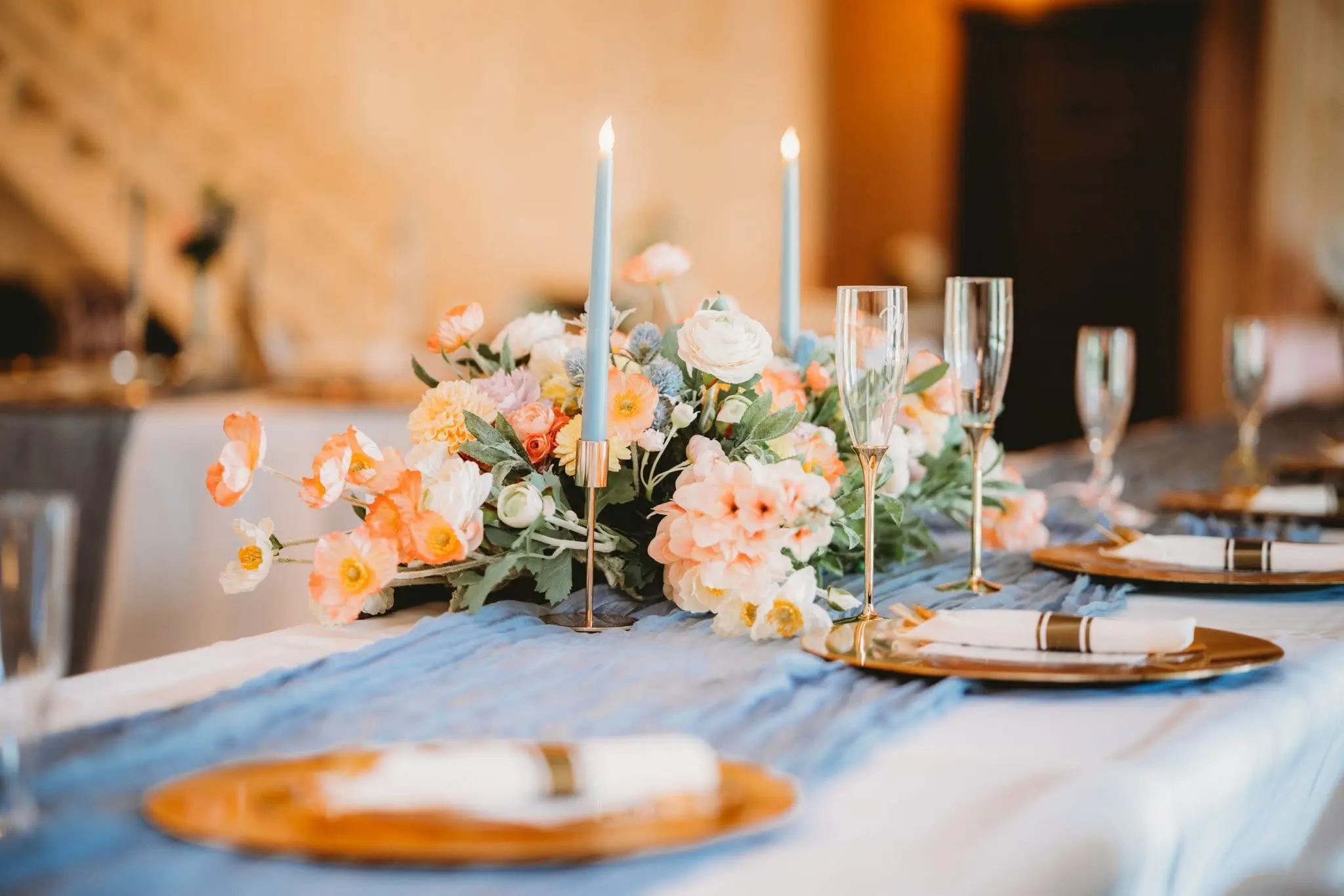 Head table styled by the Abram Farms team with a dusty-blue runner, gold chargers, and champagne flutes