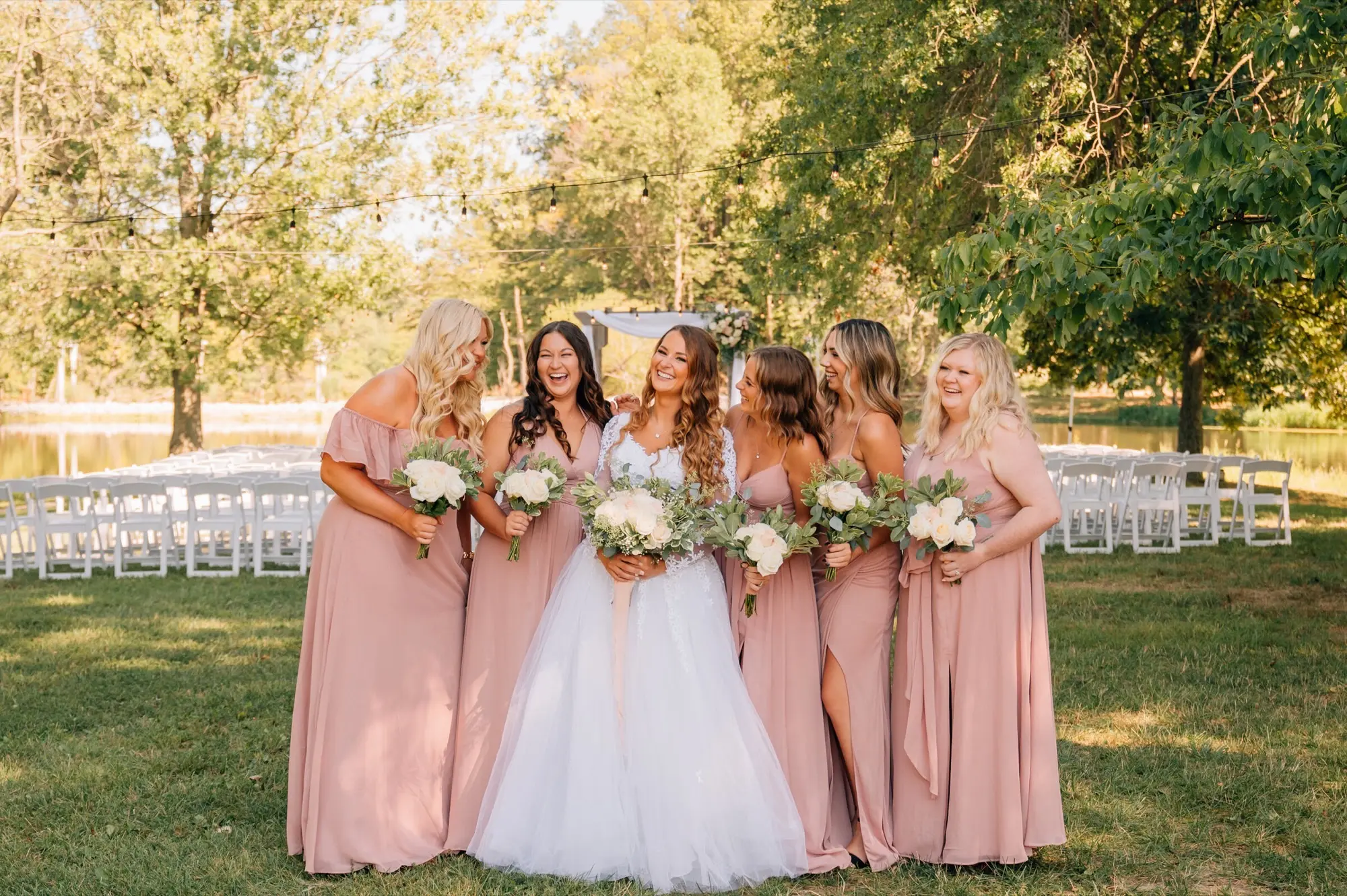 Bride and bridesmaids by the pond ceremony site at Abram Farms