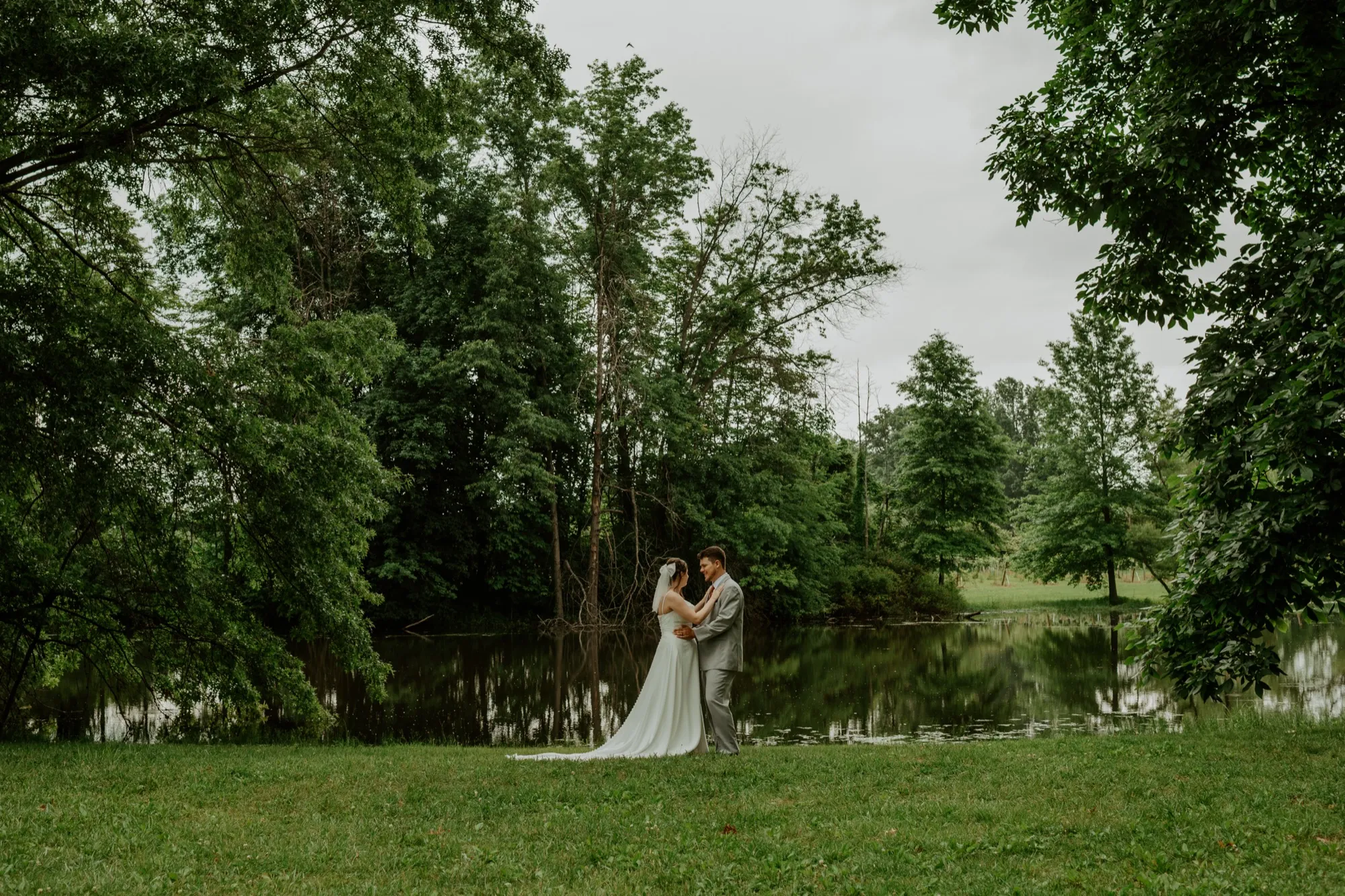 Couple by the pond among the trees at Abram Farms